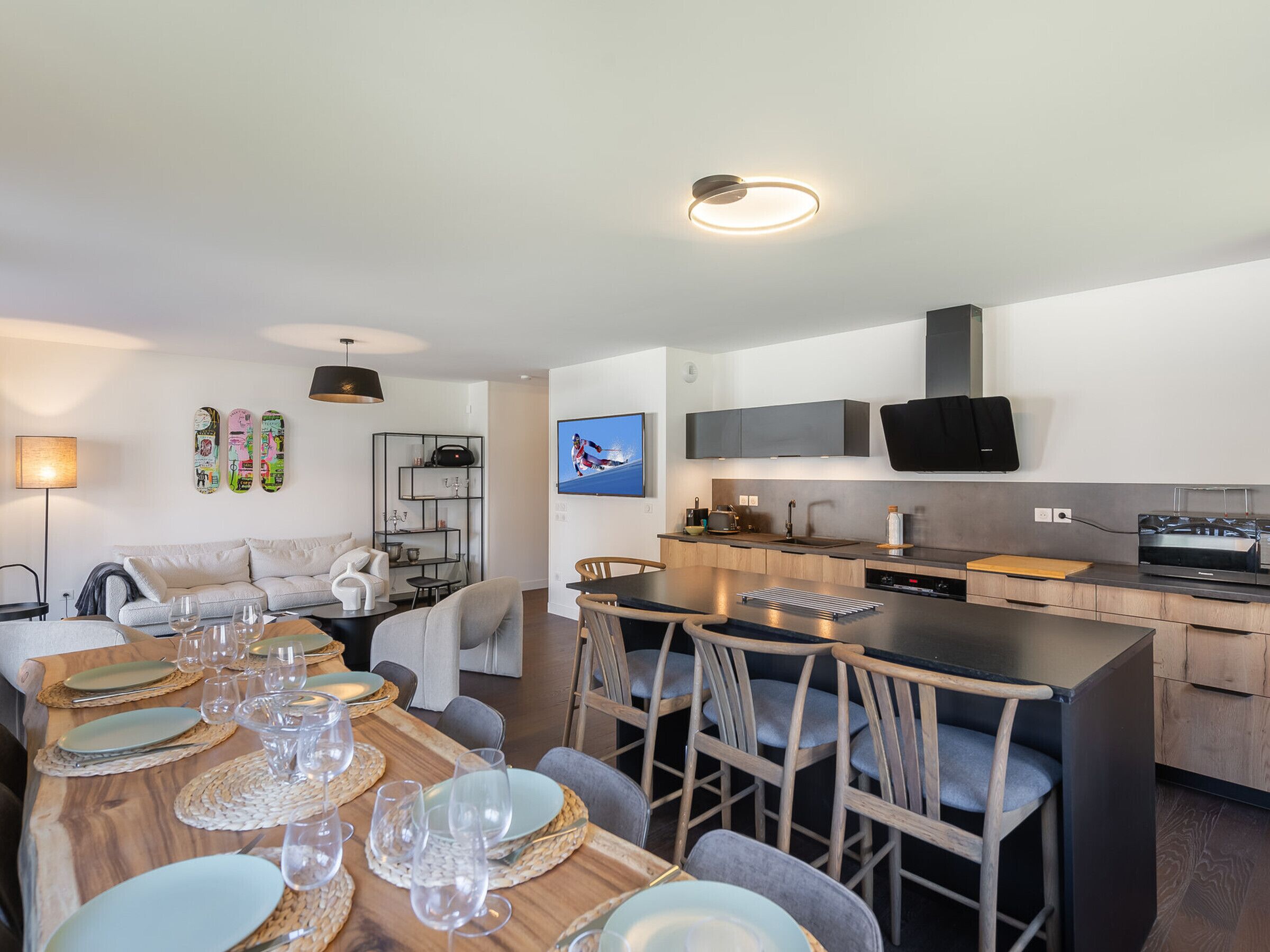 A modern kitchen with a central island, built-in appliances, and a dining area with a wooden table set for six.