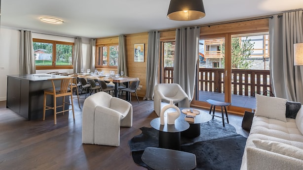 Un salon moderne avec un coin repas, un plancher en bois et de grandes fenêtres donnant sur l’extérieur.