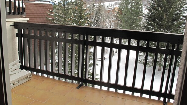 A balcony with a black railing overlooking a snowy landscape with trees and buildings. - Cozy Studio for 4 with Balcony, Close to Slopes in Serre Chevalier (La Salle-les-Alpes)