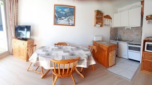 A compact kitchen with a dining area, wooden cabinets, a microwave, and a television. - Cozy Studio for 4 with Balcony, Close to Slopes in Serre Chevalier (La Salle-les-Alpes)