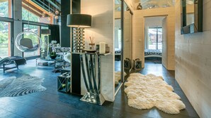 Een modern interieur met een hangstoel, een reflecterend kunstwerk en een grote spiegel.