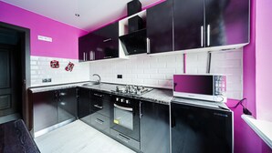 Une cuisine moderne avec des meubles noirs, un plan de travail blanc et un four à micro-ondes.