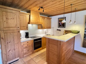 Een keuken met houten kastjes, een spoelbak, een fornuis en een klein kookeiland met een kom.