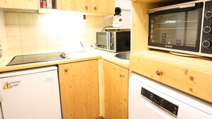 Ett kompakt kök med träskåp, en mikrovågsugn, en brödrost och en diskmaskin.