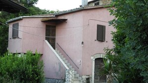 A pink building with a stone staircase leading to a door, surrounded by greenery. - HAPPY HOME (Orte)