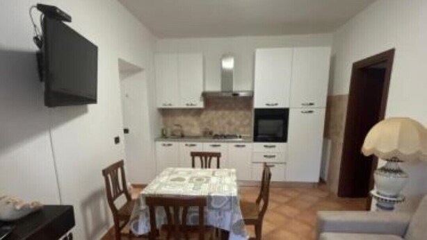 A compact living space with a dining area, kitchenette, and a sofa. - HAPPY HOME (Orte)