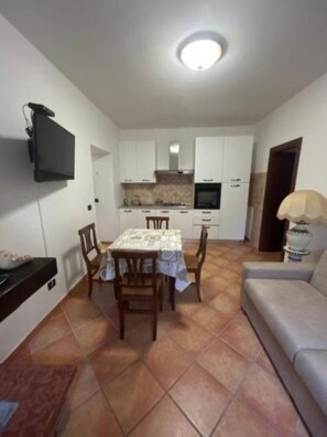 A compact living space with a dining area, kitchenette, and a sofa. - HAPPY HOME (Orte)