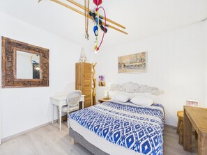 Quarto com cama, escrivaninha, cadeira, guarda-roupa e um quadro na parede.