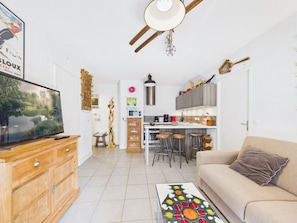 Uma sala de estar moderna com televisão, aparador de madeira e uma mesa de centro colorida.