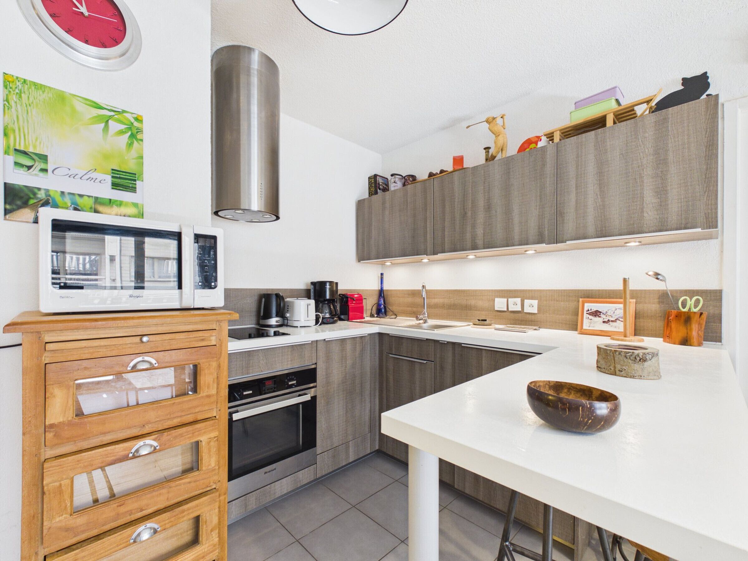 Una cocina moderna con microondas, cafetera y un armario de madera.