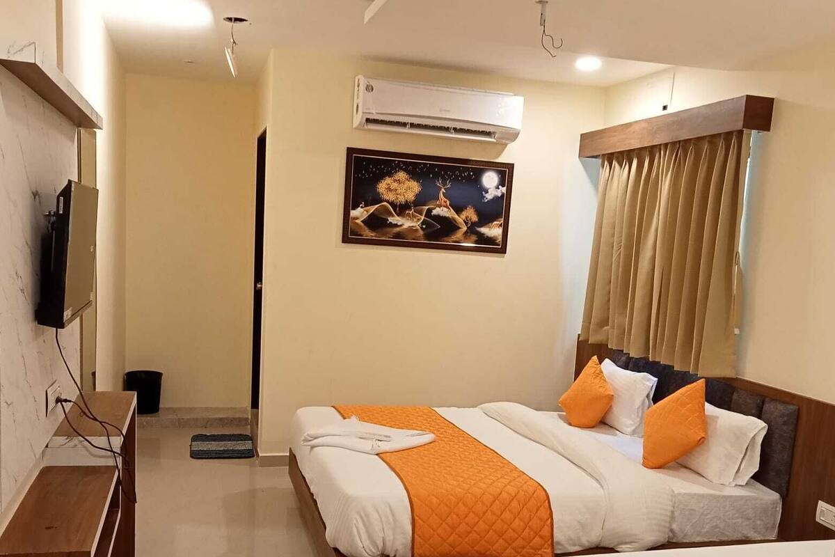 A hotel room with two beds, an air conditioning unit, a painting on the wall, and a window with curtains.