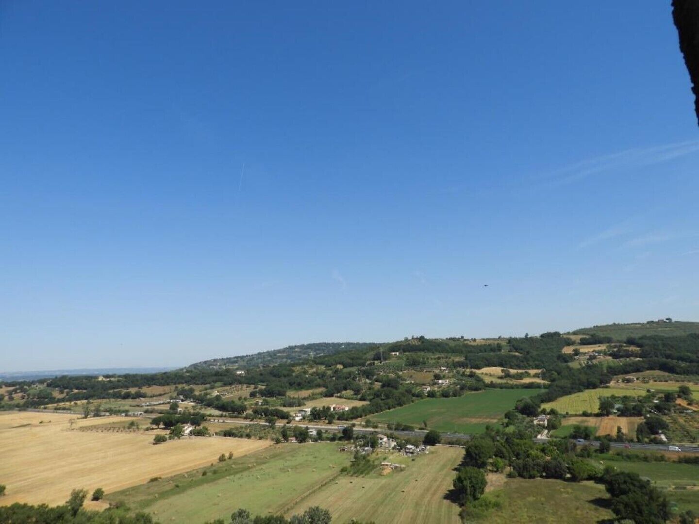 Paisatge rural amb camps, cases disperses i cel blau clar.