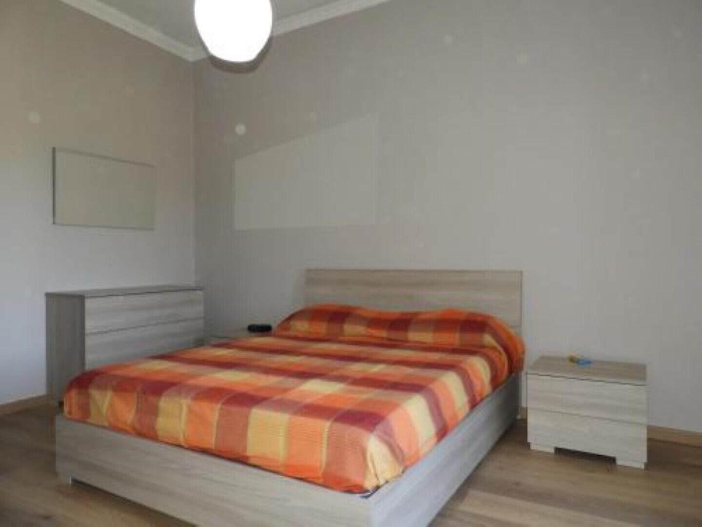 A bedroom with a bed, a bedside table, and a nightstand.