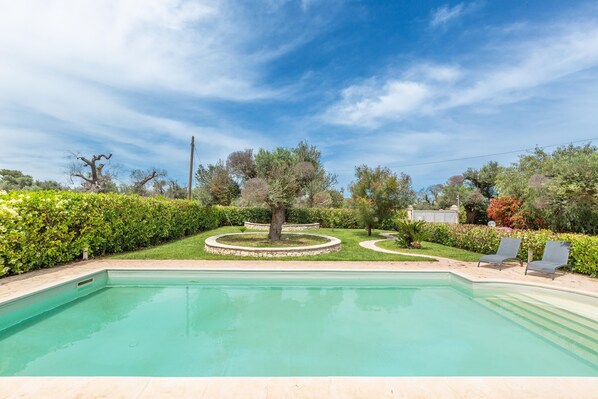 Piscina com um jardim circular e duas espreguiçadeiras.