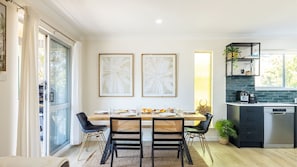 Una cocina moderna con comedor, que presenta una mesa de madera, sillas negras y una paleta de colores blanco y negro.
