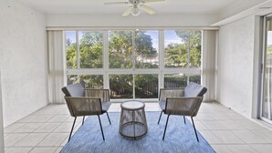 Una habitación con ventilador de techo, ventanas amplias y una mesa redonda con sillas.
