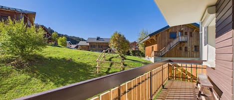 Eine Holzterrasse mit Blick auf eine grüne Landschaft und Gebäude im Hintergrund.