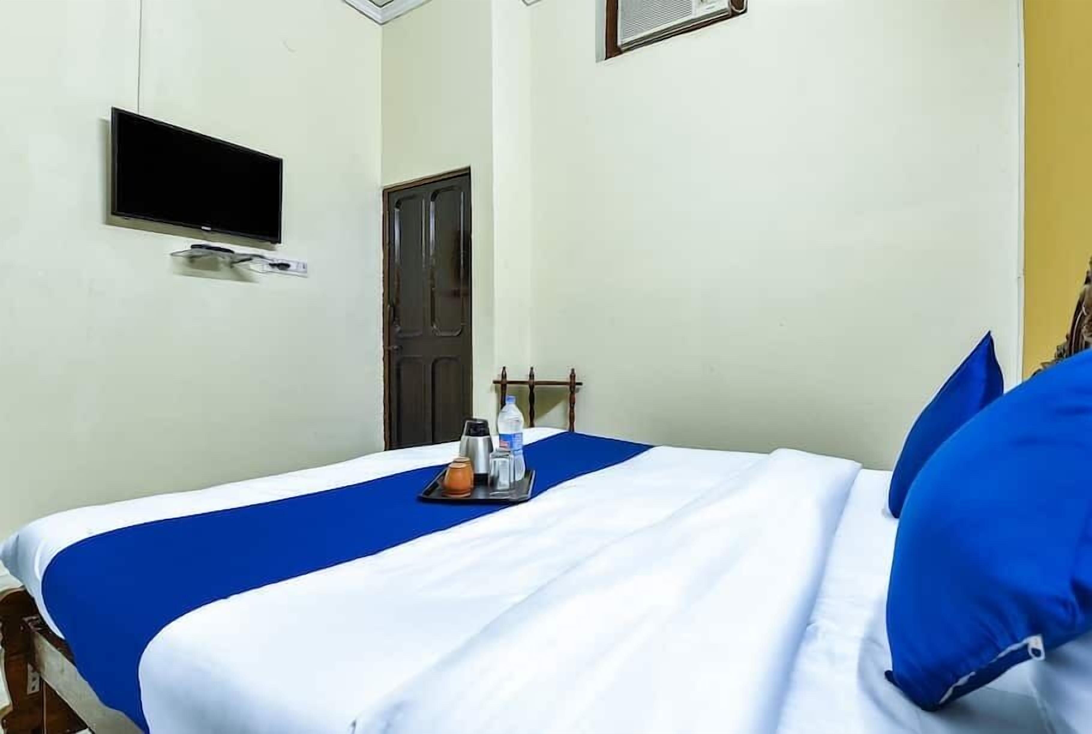 A hotel room with a bed, a flat-screen TV mounted on the wall, a door, and a window.