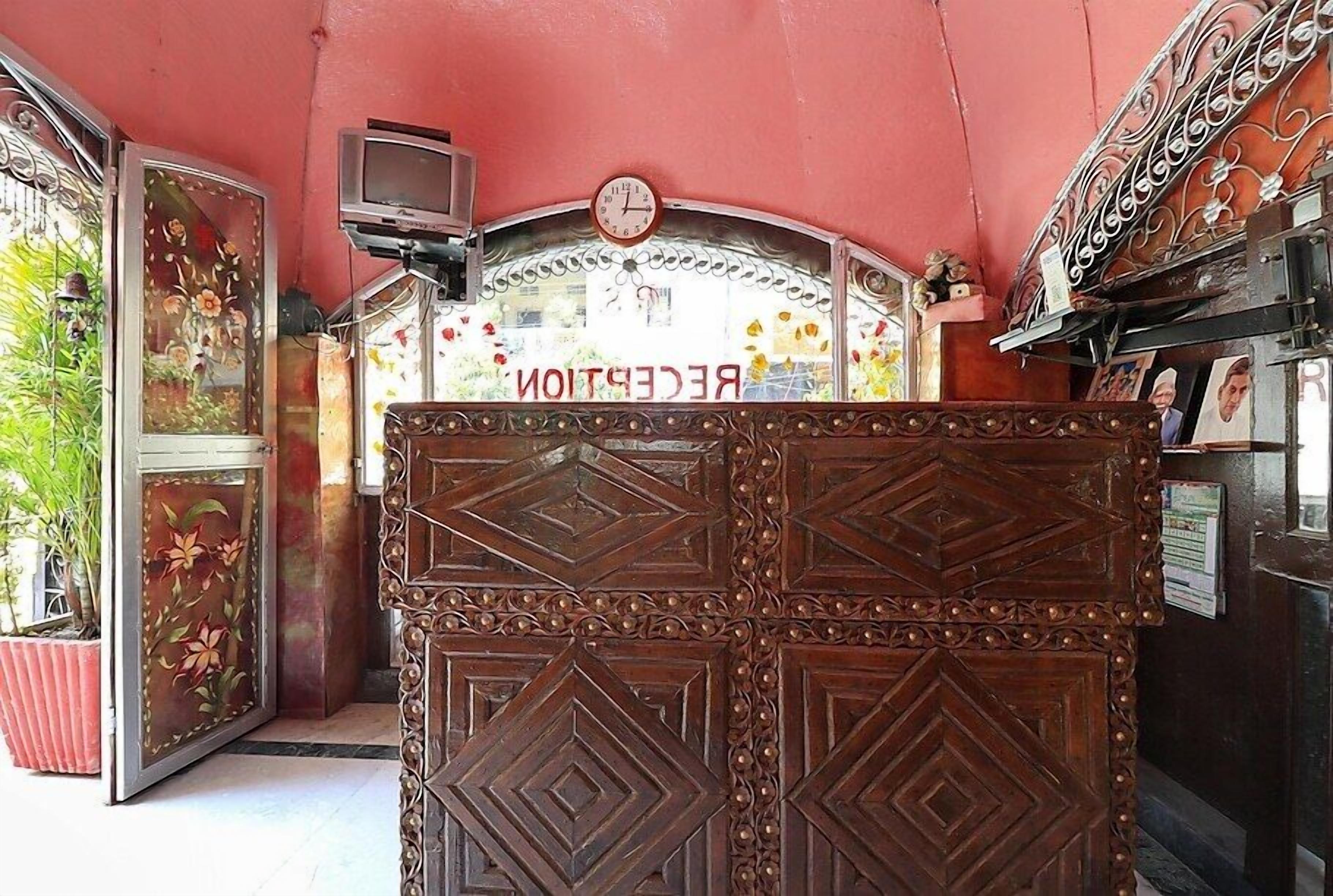 A reception area with a wooden reception desk, a clock, and a TV mounted on the wall.