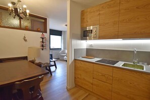 A modern kitchen with wooden cabinetry, a built-in microwave, and a stainless steel sink. - Fevri 109 Appartamento (Madonna di Campiglio)