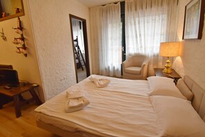 A hotel room with a bed, a chair, a desk with a computer, and a lamp. - Fevri 109 Appartamento (Madonna di Campiglio)