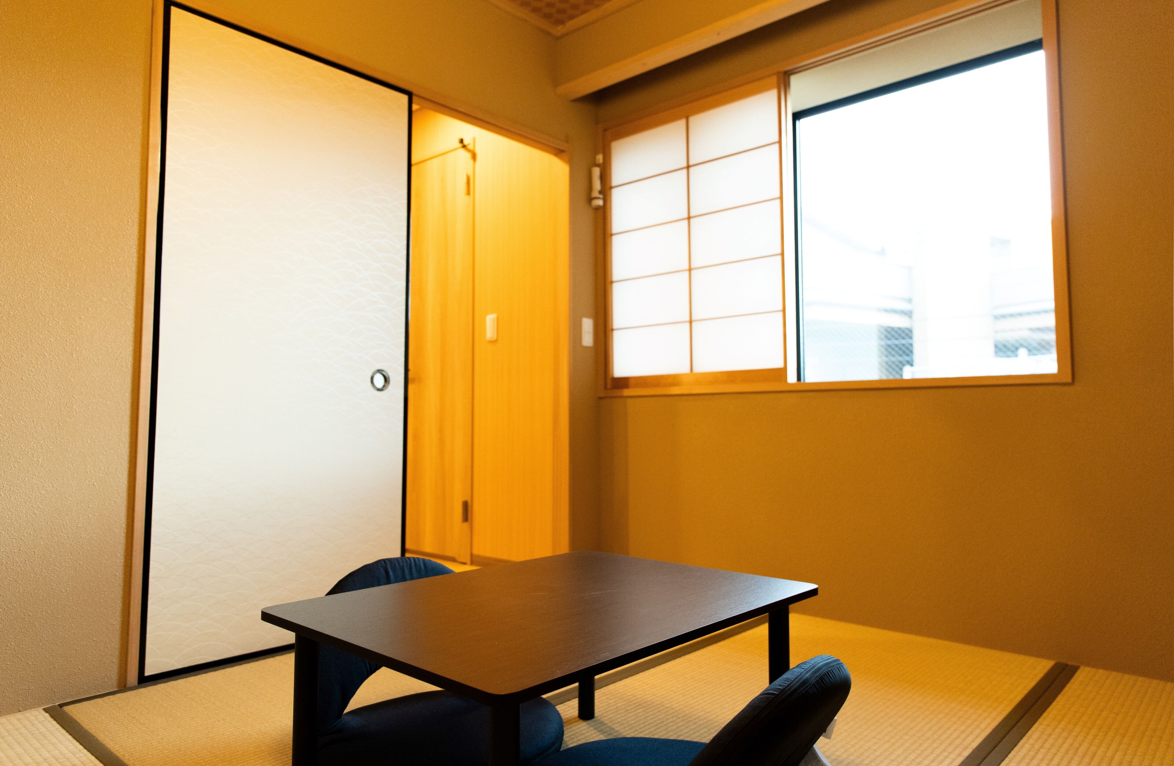 A traditional Japanese room with tatami flooring, a low table, and a sliding door.
