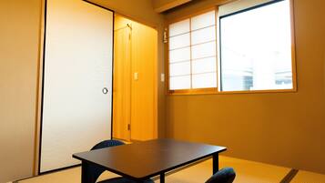 A traditional Japanese room with tatami flooring, a low table, and a sliding door.