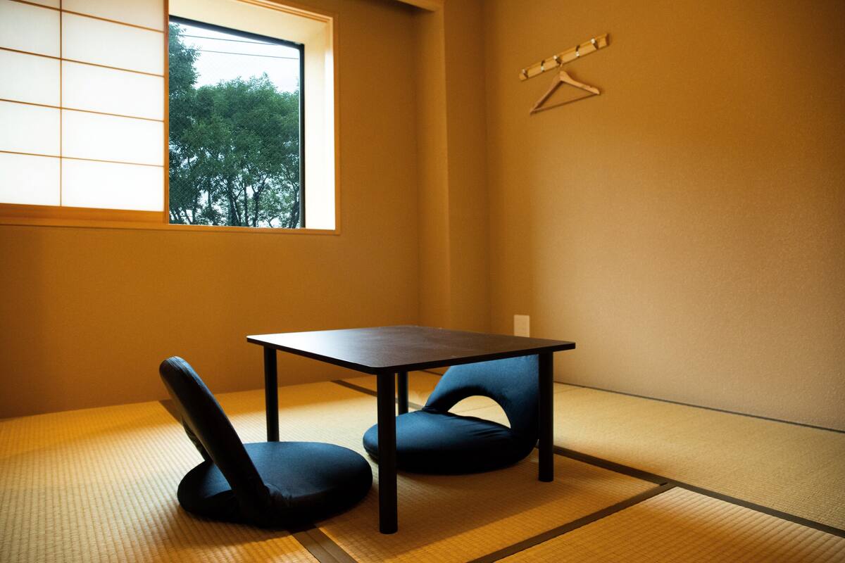 Une pi èce avec un sol recouvert de tatamis, une petite table et deux chaises.