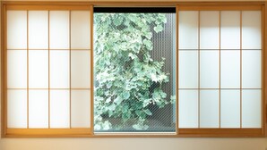 A shoji screen with a view of green foliage through a mesh window.