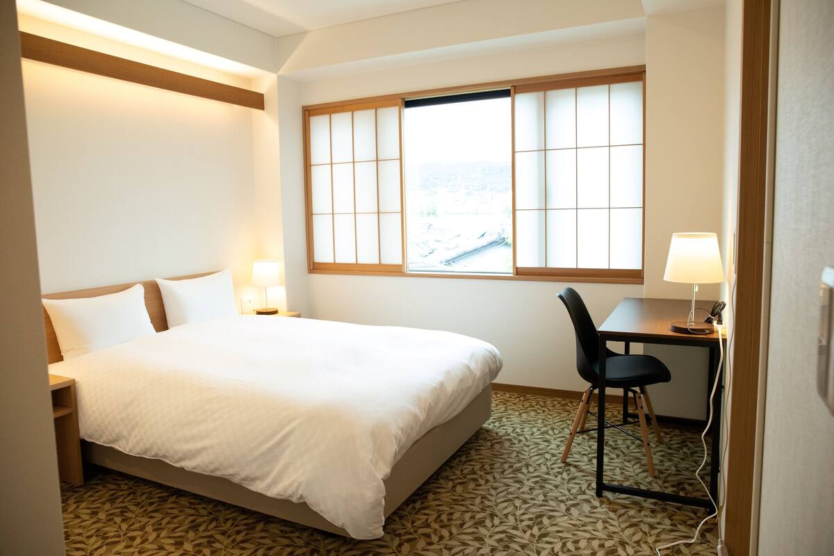 Une chambre d’hôtel avec un lit, un bureau et une chaise.