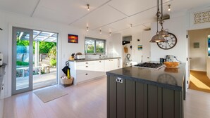 Una cocina moderna con una isla grande, armarios blancos y vistas al exterior.