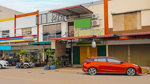 A building with a sign for 'Indomaret Coffee Roaster' and a red car parked in front.