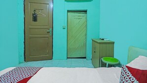 A bedroom with a bed, a wardrobe, a green chair, and two doors.