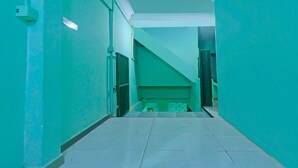 A hallway with teal walls and white tiled flooring, leading to a staircase.