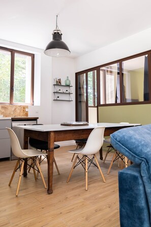 Eine moderne Küche mit einem Holztisch, weißen Stühlen und einer Pendelleuchte.