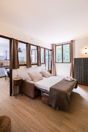 Quarto com cama, escrivaninha e vista para o exterior.