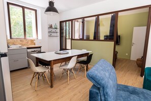 A modern kitchen with a wooden table, white chairs, and a dining area.