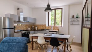 Een moderne keuken met een centraal eiland, witte kasten en een zithoek met een blauwe bank en stoelen.
