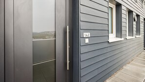 Ein modernes Gebäude mit grauer Außenverkleidung, einer großen Schiebeglastür und einem kleinen Fenster mit der Nummer 1.4.2.