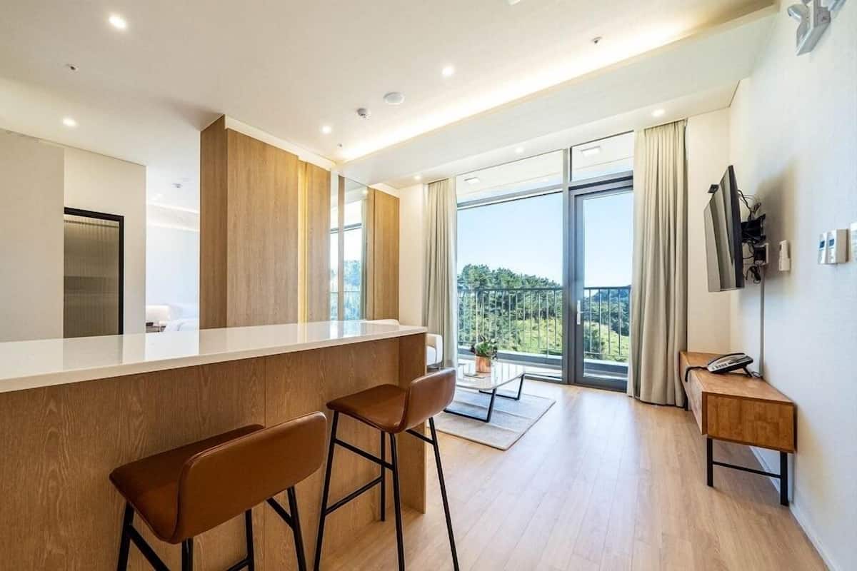 A modern kitchen with a bar area, large windows, and a view of the outdoors.