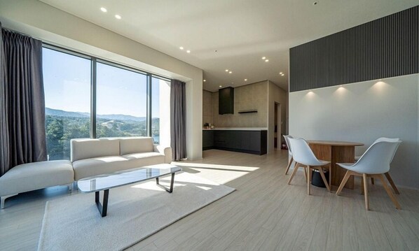 A modern living room with a sofa, a coffee table, and a dining area with chairs. - Hillsnorkelbeach Hotel (Samcheok)