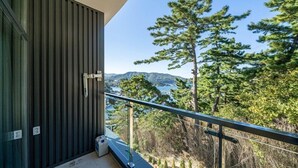 A balcony with a metal railing overlooking a mountainous landscape and a body of water. - Hillsnorkelbeach hotel (Samcheok)