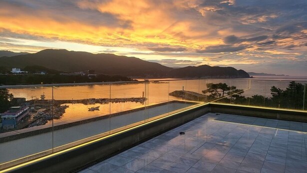 A terrace with a view of a river and mountains during sunset. - Hillsnorkelbeach hotel (Samcheok)