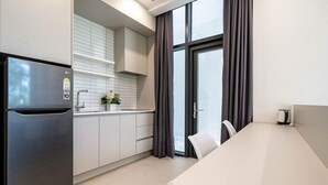 A modern kitchen with a stainless steel refrigerator, white cabinets, a white countertop, a sink, and a window with curtains. - Hillsnorkelbeach hotel (Samcheok)