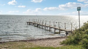 A wooden pier extending into calm waters, with a sign indicating a route or location.