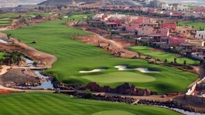 Un campo da golf con bunker, ostacoli d'acqua e una zona residenziale sullo sfondo.