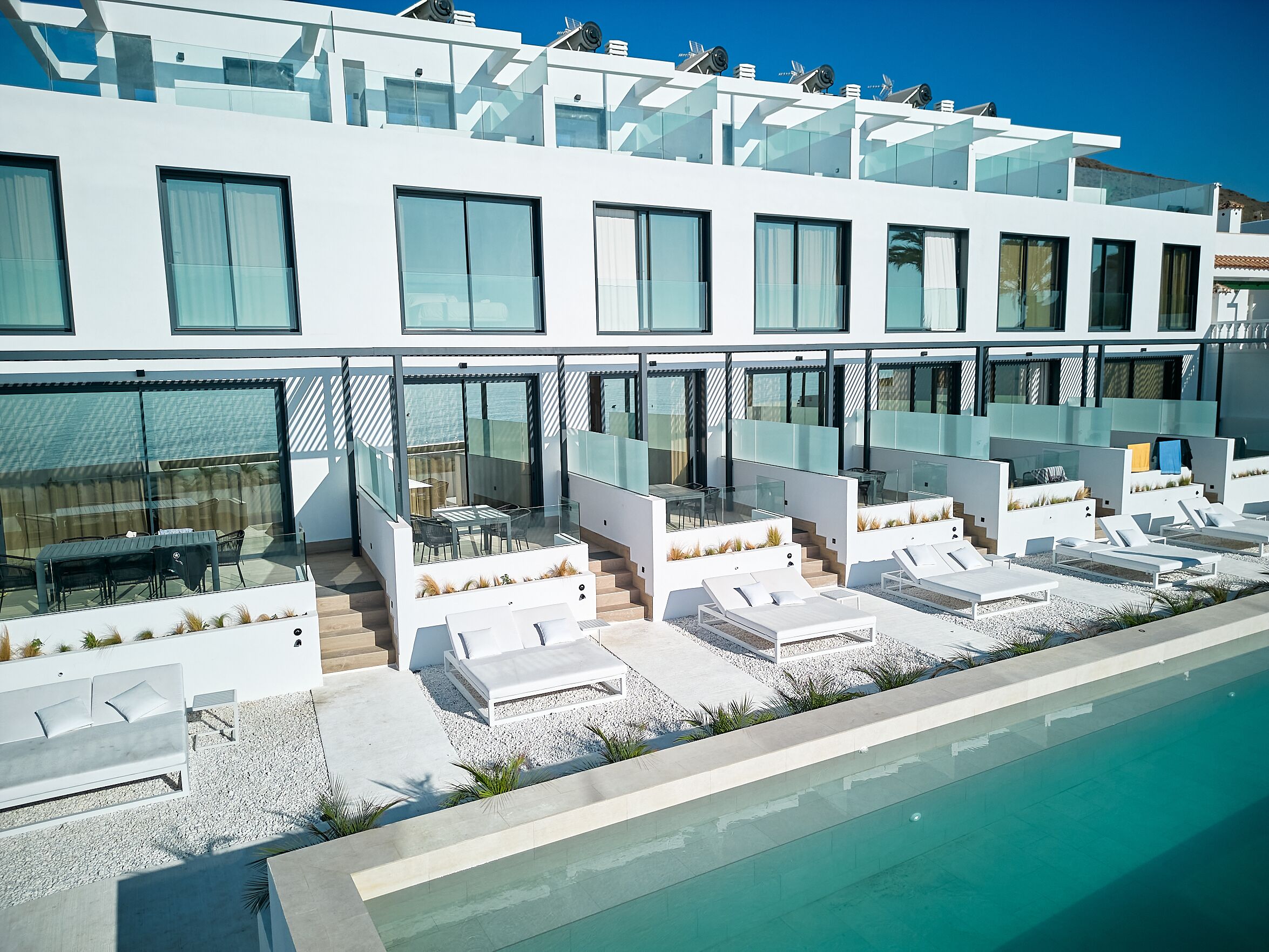 Hotel modern amb piscina, zona de seients a l'exterior i façana de vidre.