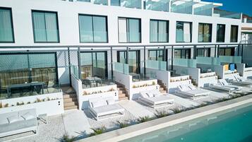 Hotel modern amb piscina, zona de seients a l'exterior i façana de vidre.