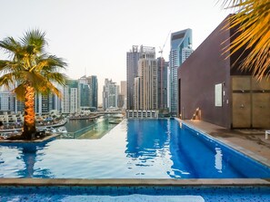 A swimming pool with a cityscape view, including high-rise buildings and a palm tree.
