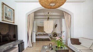 A modern living room with a flat-screen TV, a sofa, a coffee table, and a decorative plant. - 3512 Villa Mediterranea by Perle di Puglia (Ostuni)